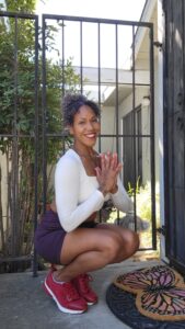 Photo depicts fitness content creator, Nadia Santiago, an Afrolatin woman performing the yoga pose toe stand